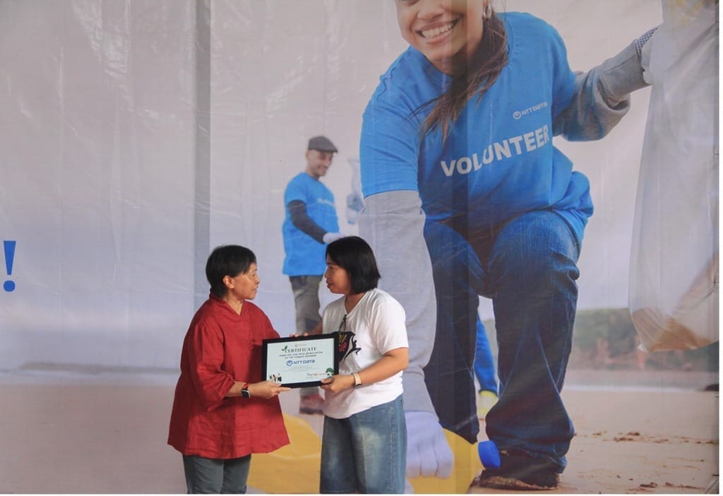 retno director of xsprojek (left), presented an environmental awareness certificate to dini, head of hr at ntt data (right).