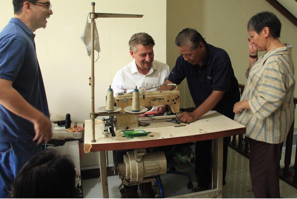 david flatard (center) is accompanied by a tailor who is guiding him through the process of sewing the fabric